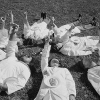O.S.O. researchers in white lab coats lie on the grass in a circle